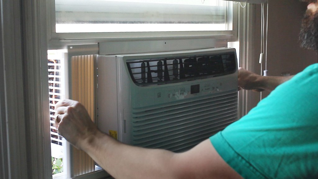 Man installing air conditioning unit in a window